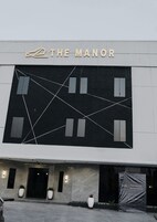 Un edificio con un letrero que dice “THE MANOR” y un diseño geométrico en la fachada.