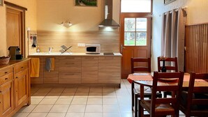 A kitchen with wooden cabinets, a microwave, and a window. - Cozy cottage with sauna, near Loire castles (Pouillé)
