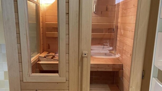 A wooden sauna room with a glass door, a bench, and a sink. - Cozy cottage with sauna, near Loire castles (Pouillé)