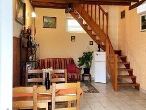 A cozy living room with a wooden staircase, a sofa, a dining table, and a refrigerator. - Cozy cottage with sauna, near Loire castles (Pouillé)