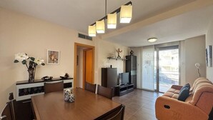 A modern living room with a sofa, a dining table, and a TV.