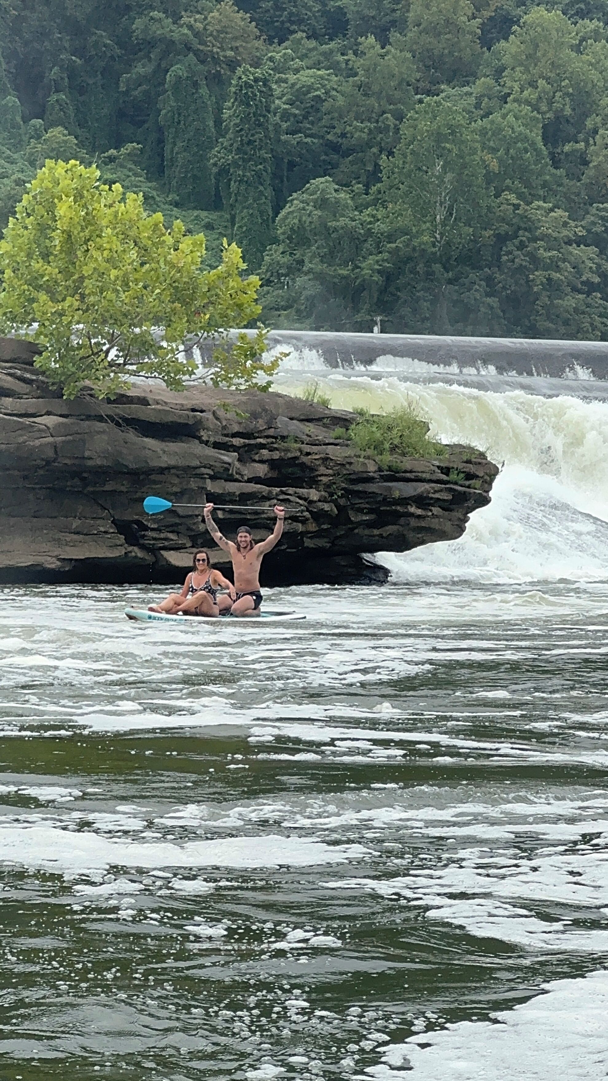 A river with a rocky outcrop where two people are kayaking.