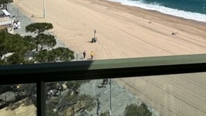 Una spiaggia con vista chiara sulla battigia, alcune persone e un lampione.