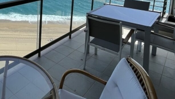 Un balcone con vista sulla spiaggia e sull'oceano. Si notano poltrone in vimini e un tavolo.