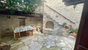 A stone courtyard with a table and chairs, a small archway, and potted plants. - Juliet Studio Suite by TrulyCyprus (Dhoros)