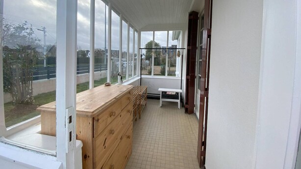 Een smalle gang met een houten bankje, een klein tafeltje en een houten dressoir.