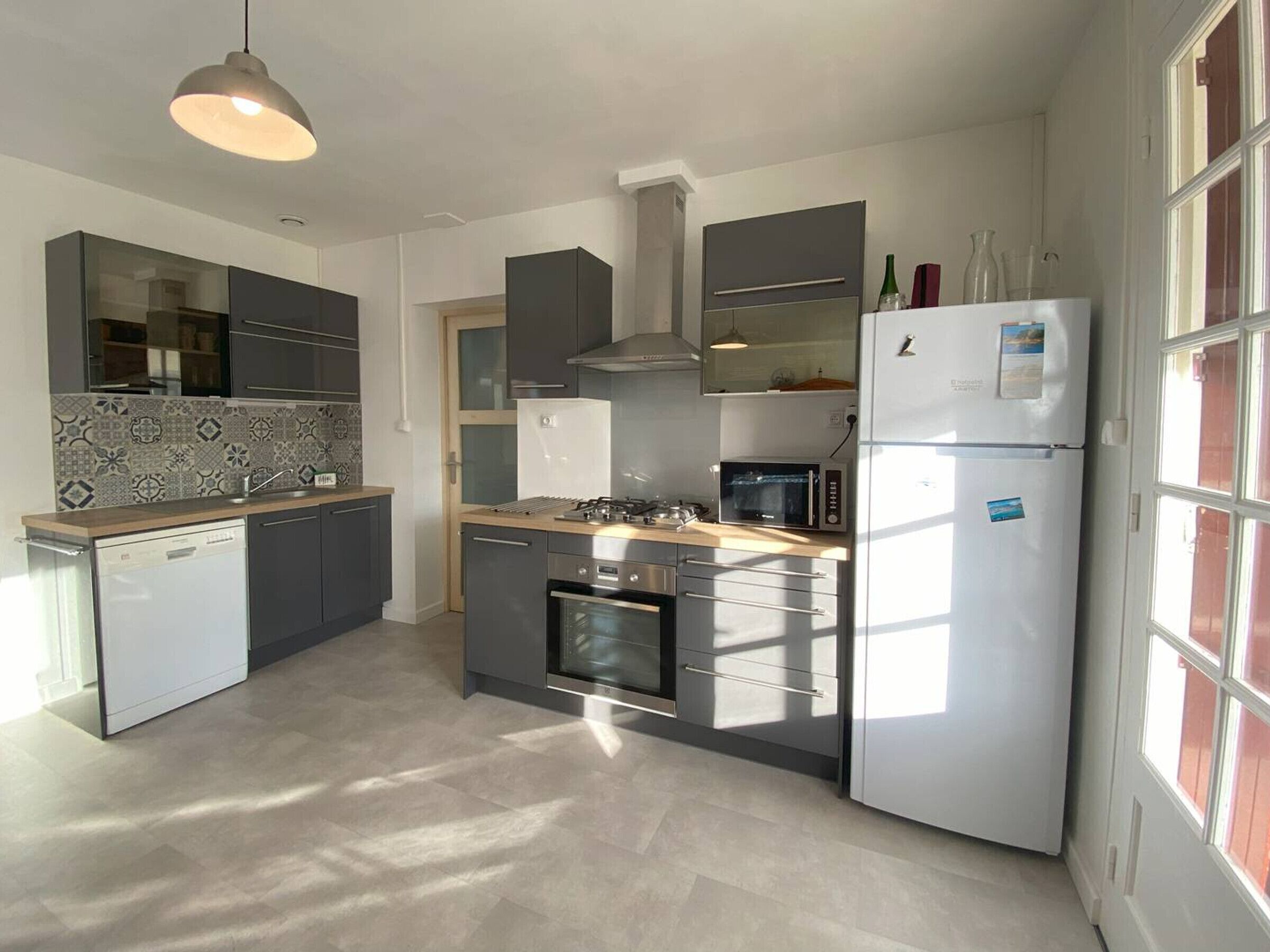 A modern kitchen with a dishwasher, oven, microwave, and a refrigerator.