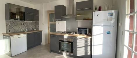 A modern kitchen with a dishwasher, oven, microwave, and a refrigerator.