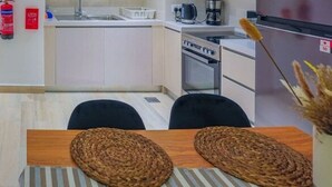 Eine moderne Küche mit Herd, Backofen und Kaffeemaschine. Auf dem Tisch liegen zwei gewebte Untersetzer.