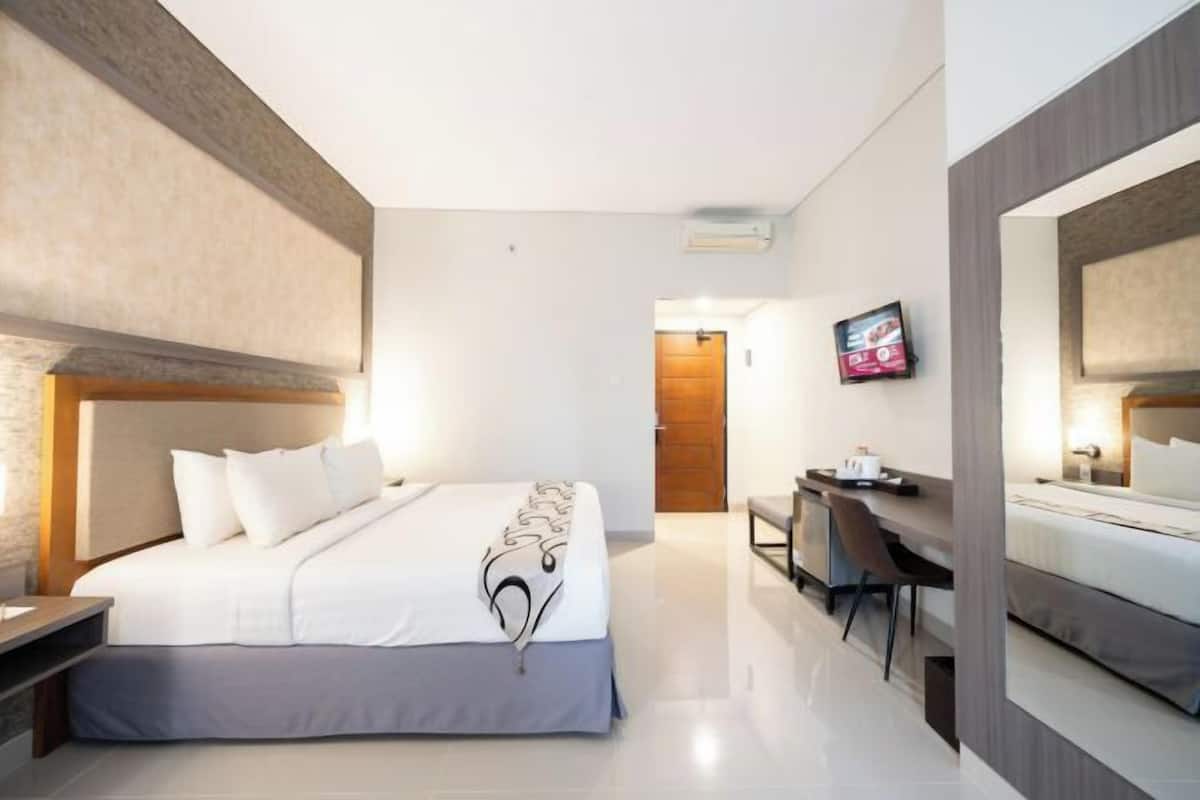 A modern hotel room with a large bed, a desk, and a television.