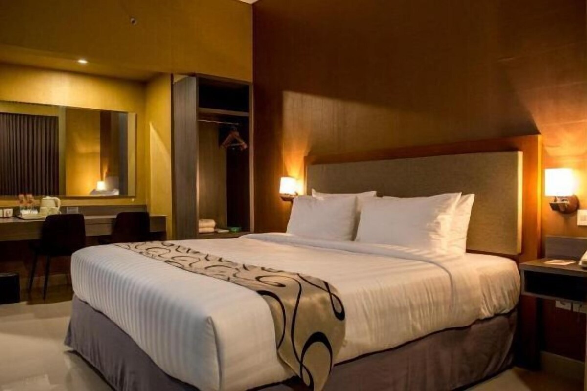 Une chambre d’hôtel avec un grand lit, un bureau et un miroir.