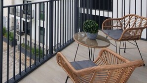 En balkon med fletstole, et rundt bord og en potteplante.
