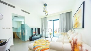 Una sala moderna con un sofá modular, un televisor y una zona de comedor.