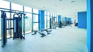 A modern gym with various exercise equipment, large windows, and a clean, spacious layout. - Bloomfields STU Balcony Azizi Riviera Meydan (Dubai)