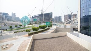 Una zona urbana moderna con grúas de construcción, un estadio y un gran edificio de vidrio.