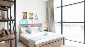 Un dormitorio moderno con una cama de madera, ropa de cama blanca y un amplio ventanal con cortinas.