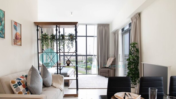 Una sala de estar moderna con sofá, mesa de comedor y sillas. Tiene un balcón con vistas a la ciudad.