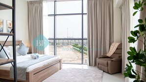 Habitación de hotel moderna con un ventanal grande, cama, sofá y vistas al aeropuerto.