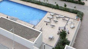 Ein Poolbereich auf dem Dach mit Liegestühlen und einem kleinen Tisch.