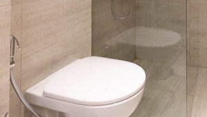 Een moderne badkamer met een wit toilet, een douchegedeelte en betegelde muren.