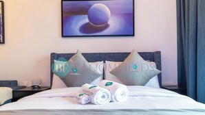 Een hotelkamer met een net opgemaakt bed, kussens en een ingelijst kunstwerk aan de muur.