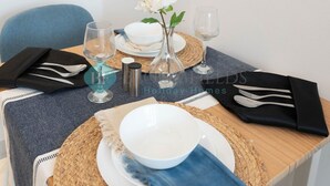 Una mesa de comedor impecable con un bol blanco, un florero con una flor blanca y una botella de agua.
