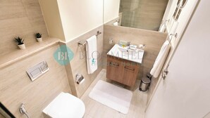 Une salle de bain moderne équipée d’une douche, de toilettes, d’un meuble-lavabo et d’un petit lavabo.
