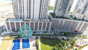 Un immeuble résidentiel de grande hauteur doté de nombreux balcons, d’un jardin sur le toit et d’une piscine.