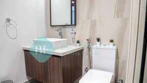 A modern bathroom with a wooden vanity, a white sink, a mirror, and a toilet. - Bloomfields Stylish 1BR in Reflections Al Reem (Abu Dabi)
