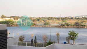 A view of a body of water with a distant landscape, including trees and buildings. - Bloomfields Stylish STU in Waters Edge Yas Island (Abu Dabi)