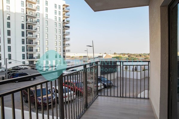A balcony with a view of a parking area and a tall residential building. - Bloomfields Stylish STU in Waters Edge Yas Island (Abu Dabi)