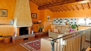 A cozy living room with a fireplace, a sofa, and a dining area with a table and chairs. - Cottage - The Hill Below - Imagine a place just for you (Toscana)
