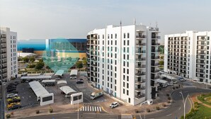 Ein moderner Apartmentkomplex mit mehreren Hochhäusern, einem Parkplatz und einer Kreuzung.