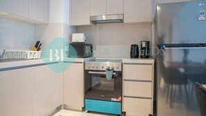 A modern kitchen with a built-in oven, a coffee machine, and a stainless steel refrigerator. - Bloomfields Modern 1BR in Waters Edge Yas Island (Abu Dabi)