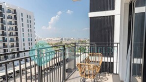A balcony with wicker chairs, a view of a cityscape, and a building with balconies. - Bloomfields Modern 1BR in Waters Edge Yas Island (Abu Dabi)
