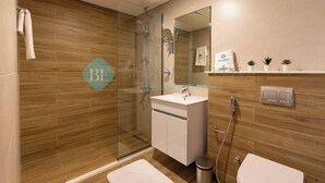 A modern bathroom with a glass shower enclosure, a white sink, and a mirror above it.