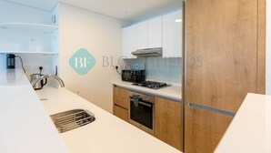 A modern kitchen with white cabinets, a stainless steel sink, and a built-in oven.