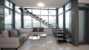 A modern living room with a sofa, coffee table, and a staircase leading to an upper floor.