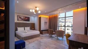 Habitación de hotel moderna con una cama grande, un escritorio y una silla. Hay una ventana con cortinas y vistas a edificios.