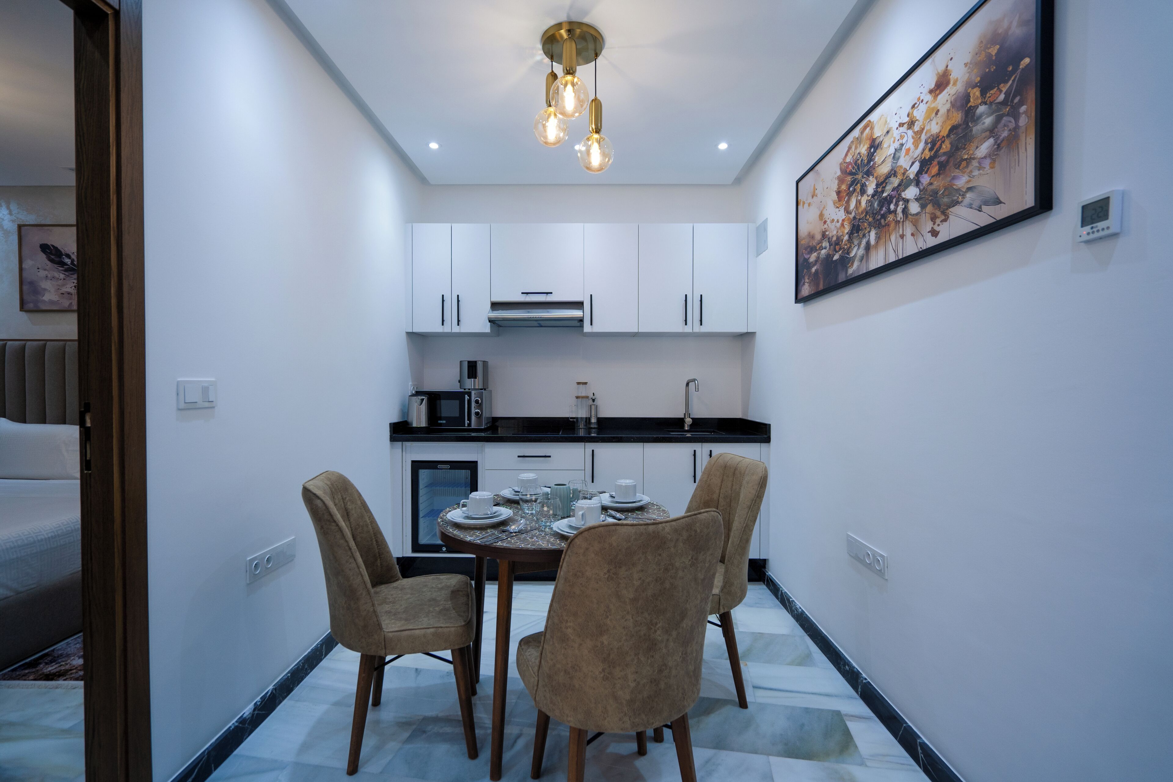 A modern kitchen with white cabinets, a dining table with chairs, and a ceiling light fixture.