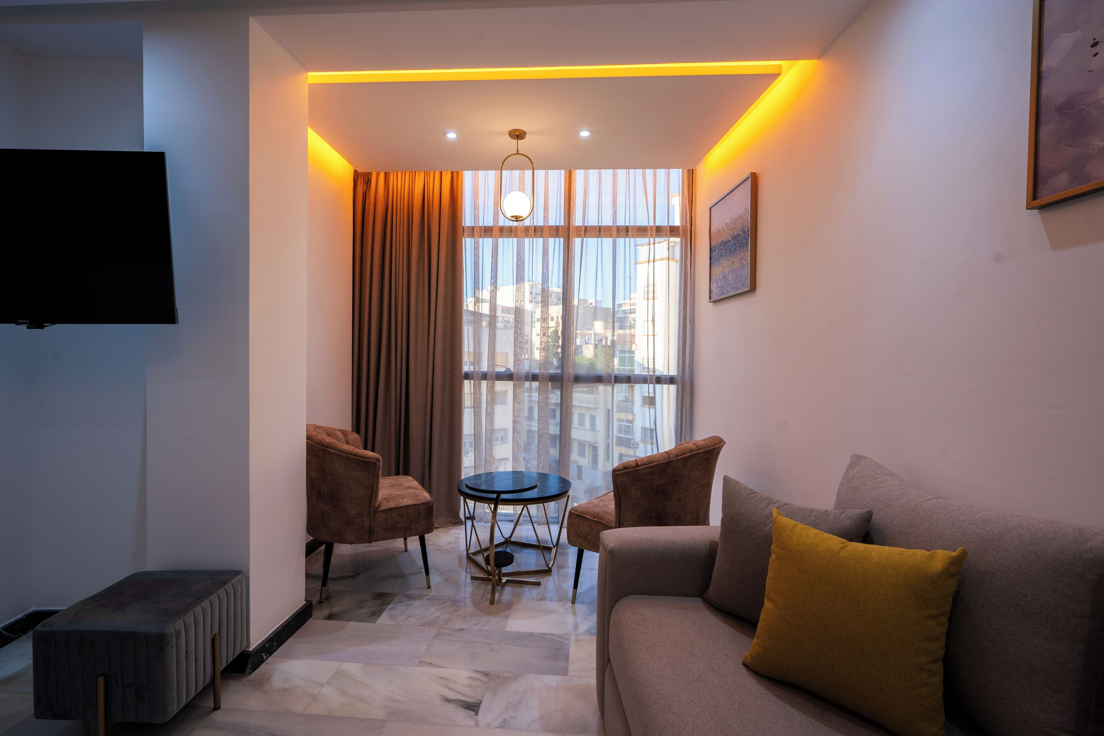 Una sala de estar moderna con un sofá, sillones, una mesa de centro y un televisor montado en la pared.