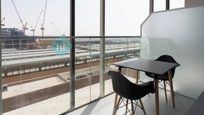 Een moderne kamer met grote ramen, een tafel en twee stoelen.