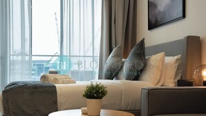 Een moderne hotelkamer met een bed, een bank, een ronde tafel en een potplant.