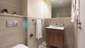 Een moderne badkamer met toilet, wastafel met spiegel en een handdoekhouder.