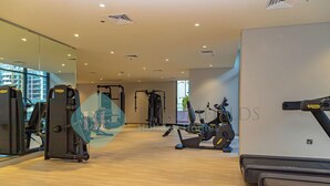 A modern gym with cardio machines, weight training equipment, and a large mirror. - Bloomfields STU View Azizi Riviera Meydan (Dubai)