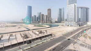 A cityscape with modern high-rise buildings, a large roundabout, and a highway. - Bloomfields Premium STU Canal View Julphar Tower (Abu Dabi)