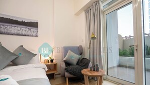 A hotel room with a bed, a chair, a small table, and a balcony with curtains. - Bloomfields STU Farishta Alfurjan near Metro (Dubai)