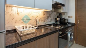 A modern kitchen with a marble backsplash, a built-in dishwasher, and a coffee maker. - Bloomfields STU Farishta Alfurjan near Metro (Dubai)