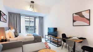 Ein modernes Hotelzimmer mit Bett, Fernseher, Esstisch und Sofa.