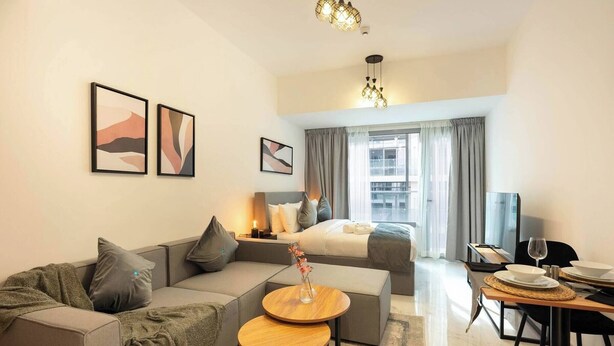 Ein modernes Hotelzimmer mit einer Couch, einem kleinen runden Tisch, einem Bett und einem Essbereich mit gedecktem Tisch für zwei Personen.